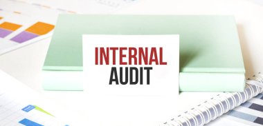 Beyaz büyük not defteri, yeşil kitap ve kâğıt sayfası üzerinde INTERNAL AUDIT yazılı mali diyagram. İş konsepti
