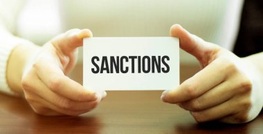Elinde SANCTIONS yazılı bir kart tutan bir işadamı