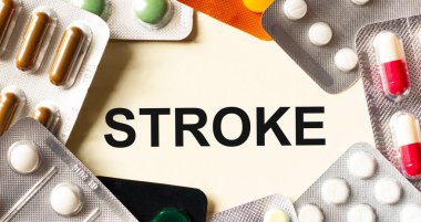 Beyaz arkaplanda STROKE mesajı. Yakınlarda çeşitli ilaçlar var. Tıbbi konsept.
