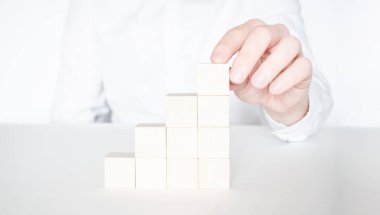 İşadamı, binanın üzerine kırmızı tahta bloğu yerleştiriyor ya da çekiyor. İş planlaması, Risk Yönetimi, Çözüm, strateji, farklı ve eşsiz kavramlar