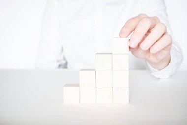 İşadamı, binanın üzerine kırmızı tahta bloğu yerleştiriyor ya da çekiyor. İş planlaması, Risk Yönetimi, Çözüm, strateji, farklı ve eşsiz kavramlar