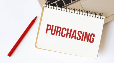 Laptop, kırmızı kalem ve beyaz arkaplanda PURCHASING yazılı not defteri