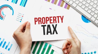 Metin Emlak Vergisi yazılı bir kart tutan bir işadamı. Klavye, diyagram ve beyaz arkaplan