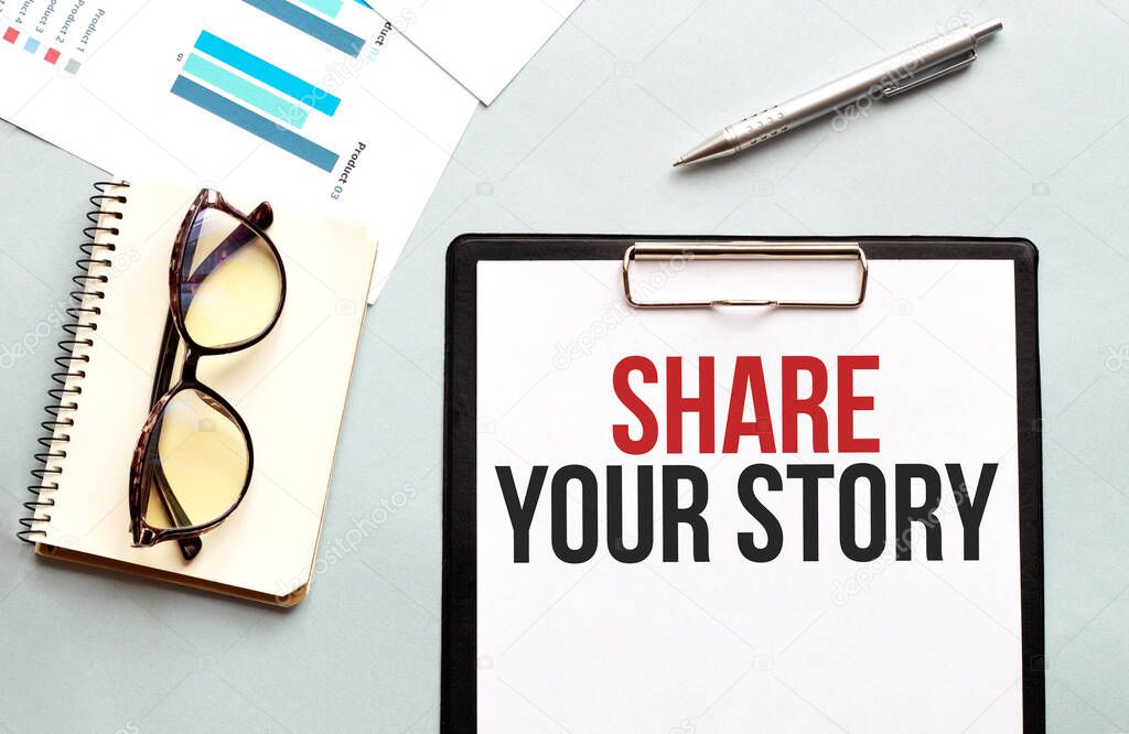 Business concept. Notebook with text Share your story sheet of white paper for notes, glasses in the white background