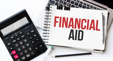 Bilgisayarın klavyesi, hesap makinesi, kalem ve not defteri beyaz arkaplanda yazılı mali yardım