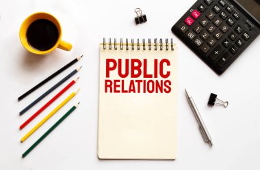 Kahve fincanı, hesap makinesi, not defteri, beyaz arka planda kalem ve kalemler. İş konsepti. Metin Halkla İlişkiler