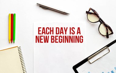 Kağıt tabak, gözlük, not defteri, beyaz arka planda kalem ve kalemler. İş konsepti. Metin Her gün yeni bir başlangıç