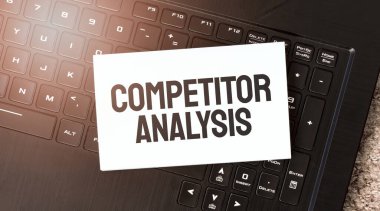 Siyah dizüstü bilgisayarda COMPETITOR ANALYSIS yazılı beyaz kağıt sayfası
