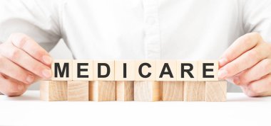 Tahta bloğu tutan bir iş adamı. İşadamı, tahta küplere yazılı tıbbi bakım ile bakıyor. Finansal. finansman