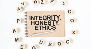 Beyaz zemin üzerinde blok tahta küpleri olan el işi renkli not defterindeki metin integrity, honeSTY, ETHICS