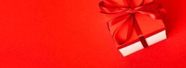 Kırmızı arka planda külahlı bir hediye kutusu. Noel arkaplanı. Üst Manzara. Metin için boşluk.