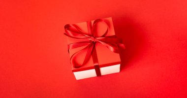 Kırmızı arka planda külahlı bir hediye kutusu. Noel arkaplanı. Üst Manzara. Metin için boşluk.