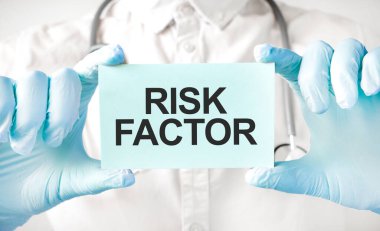 Doktor elinde kart tutuyor ve RISK FACTOR kelimesini işaret ediyor.