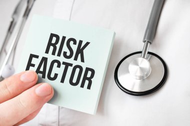 Doktor elinde kart tutuyor ve RISK FACTOR kelimesini işaret ediyor.
