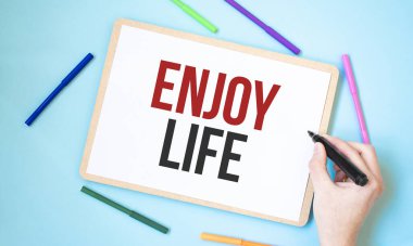 Renkli keçeli kalemlerle çevrili bir defterde hayatın tadını çıkar.,