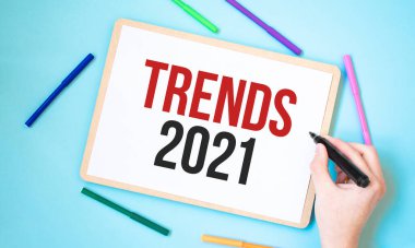 Renkli keçeli kalemlerle çevrili bir defter üzerine TRENDS 2021 metni, iş konsepti fikri,