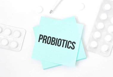 İçinde haplar, kalem, tıbbi konsept ve üst görünüm olan bir masanın üzerinde ProBIOTICS yazılı mavi kart.