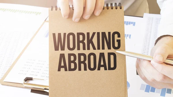 Text Working Abroad Brunt Papper Anteckningsblock Affärsman Händer Bordet Med — Stockfoto