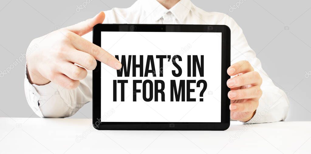 Text WHATS IN IT FOR ME on tablet display in businessman hands on the white bakcground. Business concept