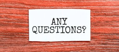 ANY QUESTIONS text on the piece of paper on the red wood background clipart