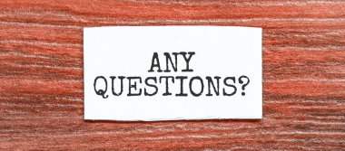 ANY QUESTIONS text on the piece of paper on the red wood background clipart