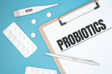 İçinde hap, kalem, medikal konsept ve üst görünüm olan bir masanın üzerinde metin PROBIOTICS olan defter sayfası