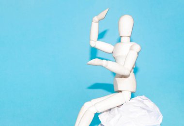 Ahşap kukla insan ellerinde peluş bir kalple kitap yığınının üzerinde oturuyor.