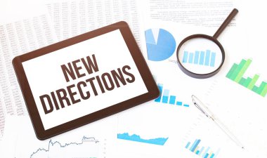 Ofis masasında büyüteçle dijital tablette grafiği inceleyen işadamının kırpılmış görüntüsü. Metin Yeni Yönler