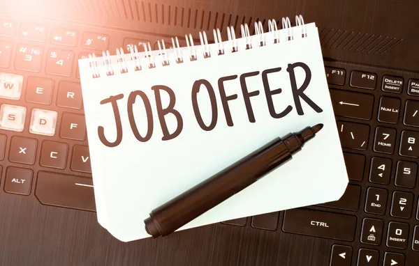 White paper sheet with text JOB OFFER on the black laptop