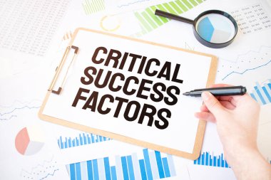 Beyaz kağıt üzerinde CRITICAL SUCCESS FACTORS ve diyagramda işadamı eli üzerinde işaretleyici metin. İş konsepti