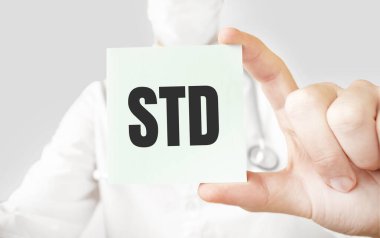 Doktor elinde kart tutuyor ve cinsel yolla bulaşan hastalık kelimesini işaret ediyor.
