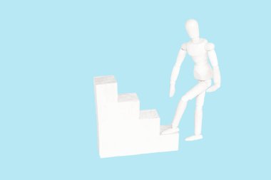 Tahta adam başarı ya da kariyer basamaklarını tırmanır. Kariyer kavramı yükseliyor, hayatta başarı, kişisel gelişim ve ilerleme. Mavi arkaplan