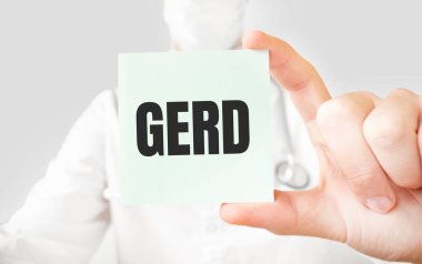 Doktor elinde kart tutuyor ve GERD kelimesini işaret ediyor.