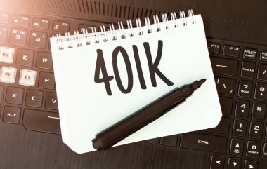 Siyah dizüstü bilgisayarda 401 K yazılı beyaz kağıt.