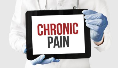 Doktorun elinde metin kronik ağrısı olan bir tablet var.