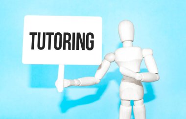 Tahta adam elinde beyaz bir tabela tutuyor. Elinde yazı var. Harflerin içeriğinin iş konsepti ve pazarlama üzerinde etkileri vardır..