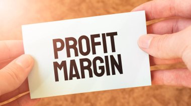 Bir iş adamının elindeki beyaz kart kâğıdına yazılmış PROFIT MARGIN kelimesi. Özet konsepti. kırmızı ve beyaz kağıt