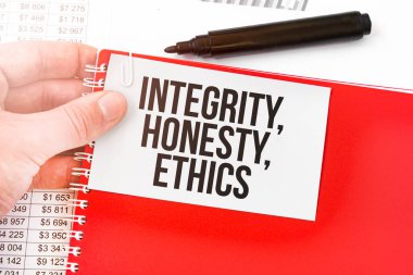 İş adamı elinde kırmızı bir defter ve beyaz bir kart tutuyor. Üzerinde de INTEGRITY, HONESTY, ETHICS yazıyor. Mali konsept
