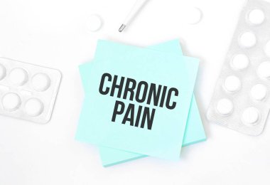 Üzerinde CHRONIC PaIN yazan mavi kart. İçinde hap, kalem, tıbbi konsept ve üst görünüm olan bir masa.