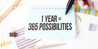 İş adamı eli, kağıt tabak, kalem, diyagram, çizelge ve ofis aletleri. Metin 1. Yıl 365 Olasılıklar