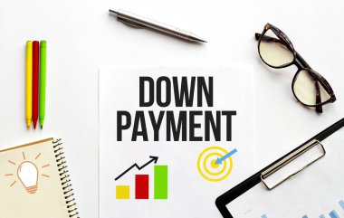 Paper plate, glasses, notepad,pen and pencils on the white background. Business concept. Text DOWN PAYMENT