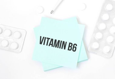 Mavi kartın üzerinde VITAMIN b6 yazılı hap, kalem, tıbbi konsept ve üst görünüm olan bir masa.