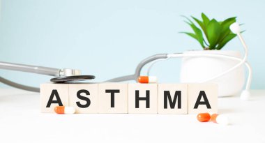 ASTHMA kelimesi ahşap bir arka planda steteskopun yanındaki tahta küplere yazılmıştır. Tıbbi konsept
