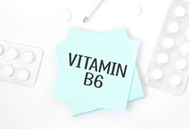Mavi kartın üzerinde VITAMIN b6 yazılı hap, kalem, tıbbi konsept ve üst görünüm olan bir masa.