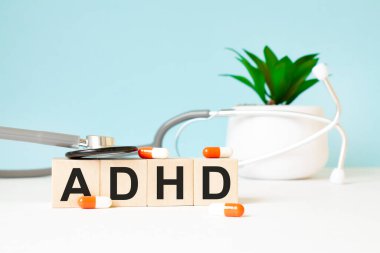 ADHD kelimesi ahşap bir arka planda steteskopun yanındaki tahta küplere yazılır. Tıbbi konsept