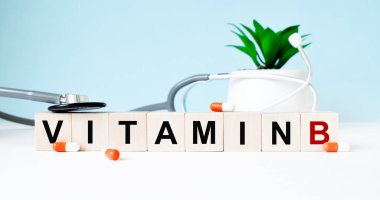 VITAMIN B kelimesi ahşap bir arka planda steteskopun yanındaki tahta küplere yazılmıştır. Tıbbi konsept