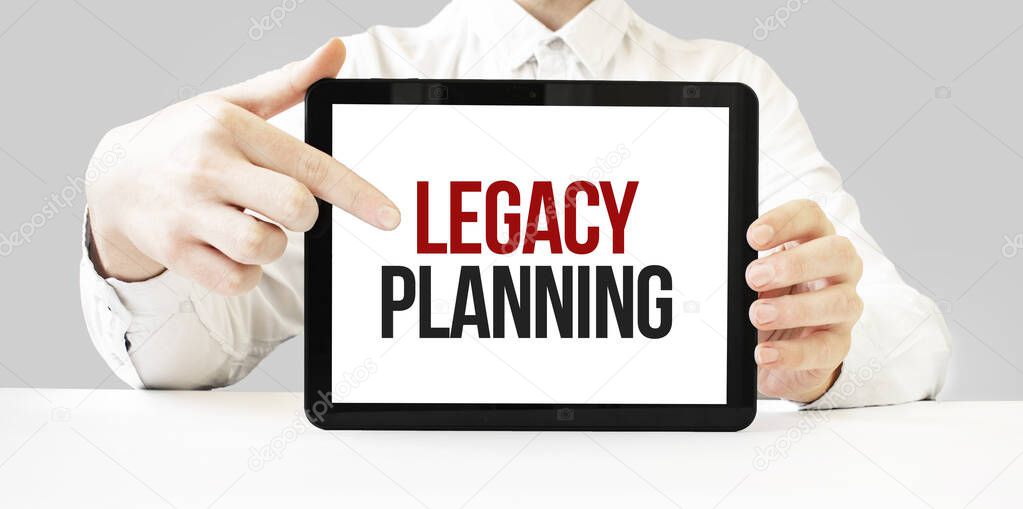 Text LEGACY PLANNING on tablet display in businessman hands on the white bakcground. Business concept