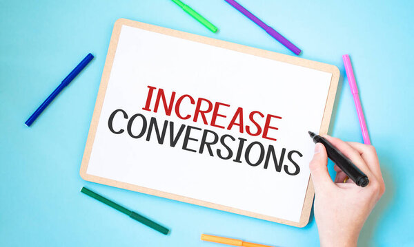 Text increase conversions on a notebook surrounded by colored felt-tip pens, business concept idea,