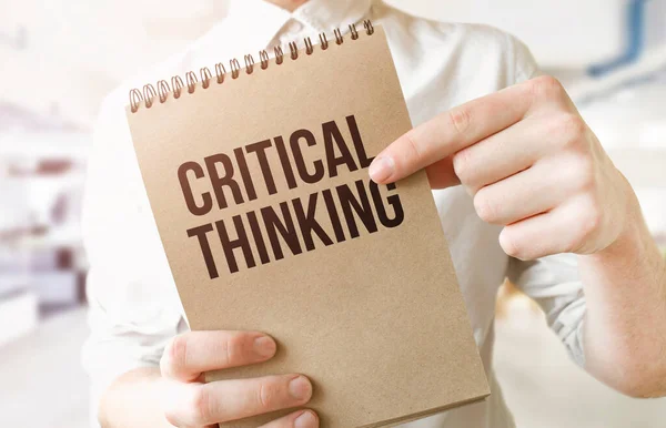Text critical thinking on brown paper notepad in businessman hands in office. Business concept