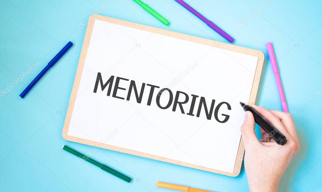 Text mentoring on a notebook surrounded by colored felt-tip pens, business concept idea,